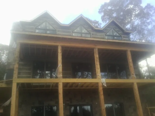 Dormers and porch framing on a large log home under construction — Roof Coating work by our crew in Altona