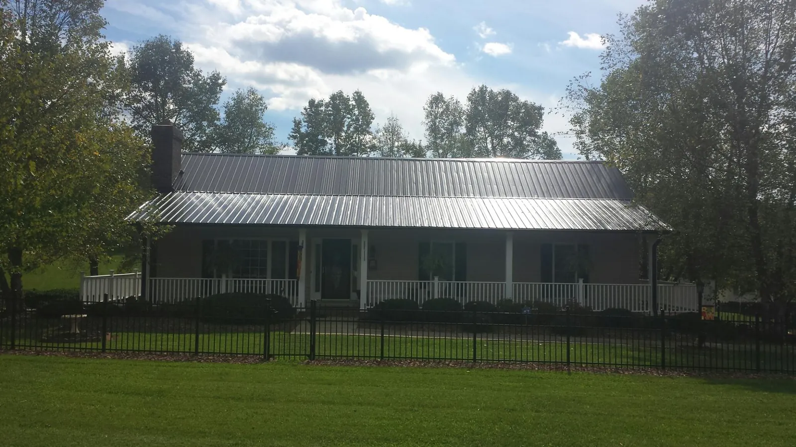 Gray metal roof on a brick ranch with a full width front porch — Gutter Guard Installation work by our crew in Altona