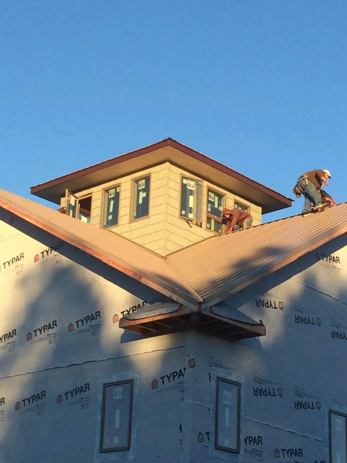Roofers working around a rooftop cupola on a new metal roof at sunset — Roof Waterproofing in Altona by Roofing Brothers